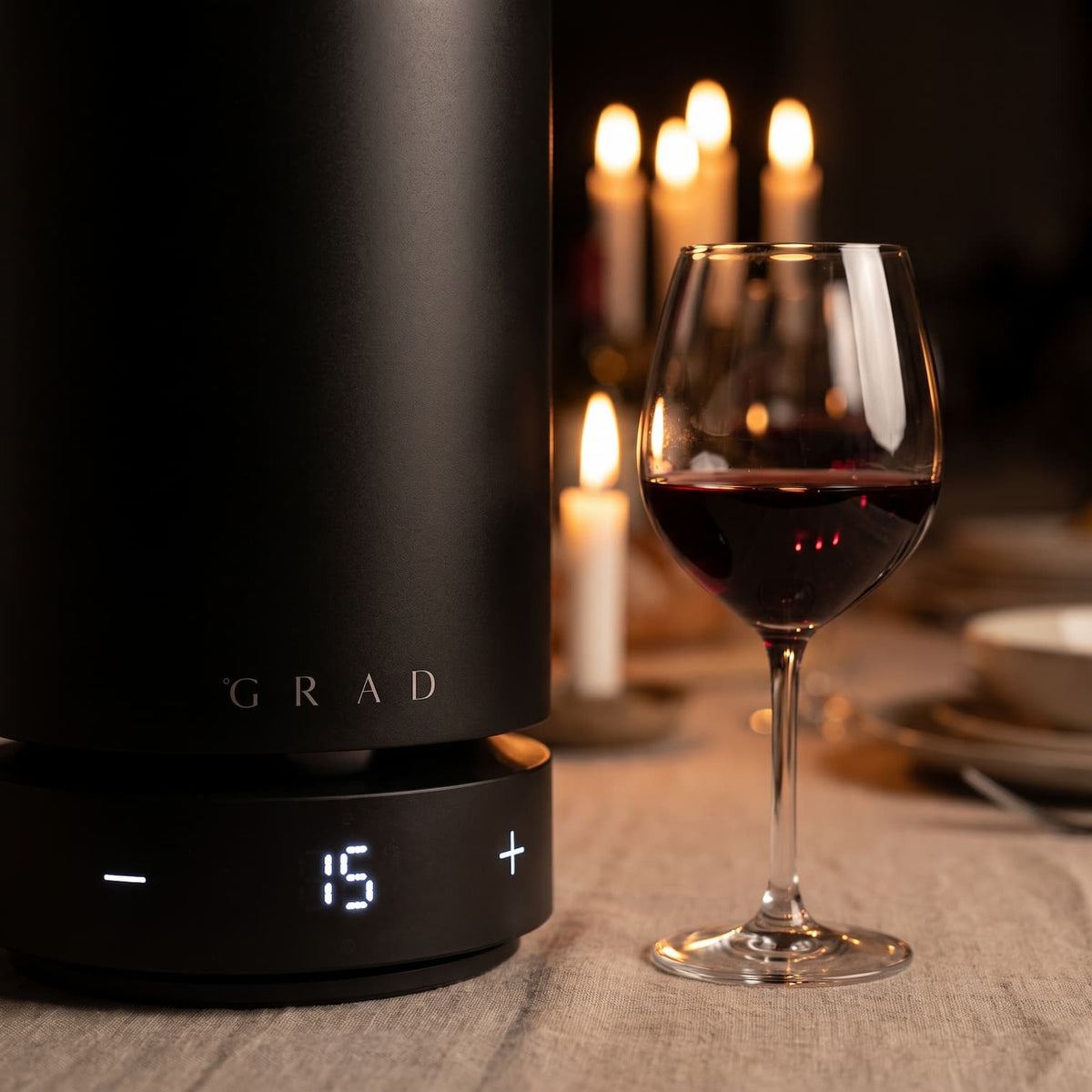 GRAD No.1 Black Edition set to 15 °C beside a glass of red wine at a candlelit dinner